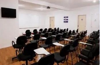 Fileiras de cadeiras com pranchetas no auditório da APAT.