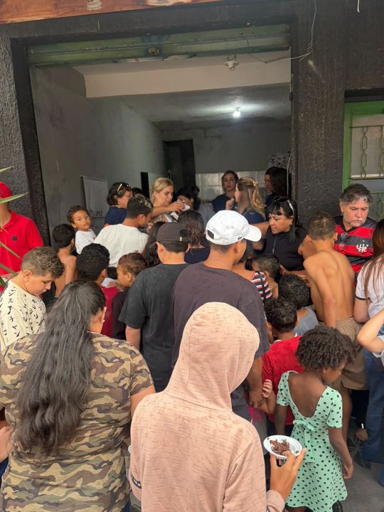 Voluntárias da APAT servindo bolo às crianças na porta do local da festa.